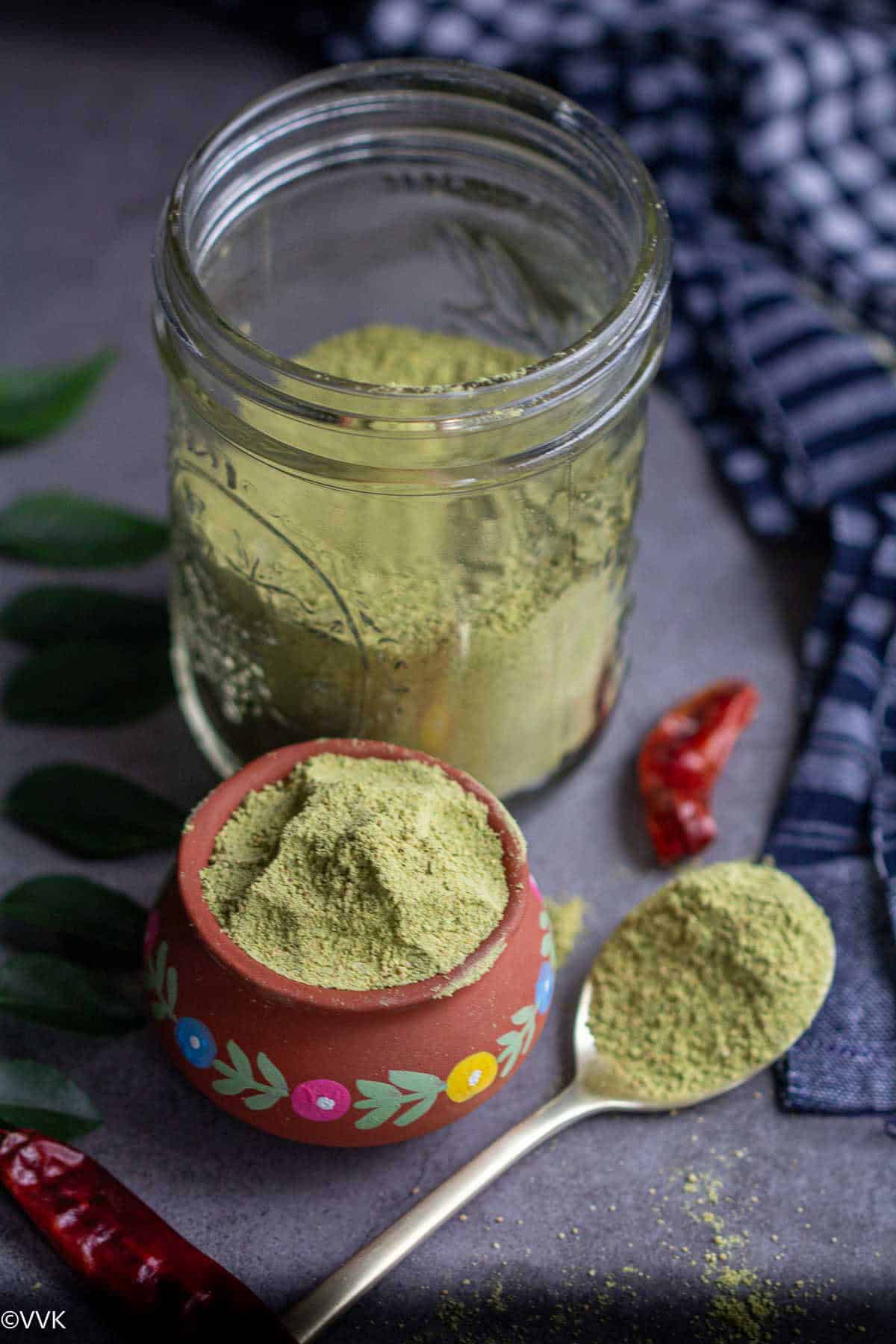 close up shot of crru leaves powder in clay pot, glass jar and and in spoon