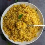 square image of raw mango rice served in white plate with spoonful of rice