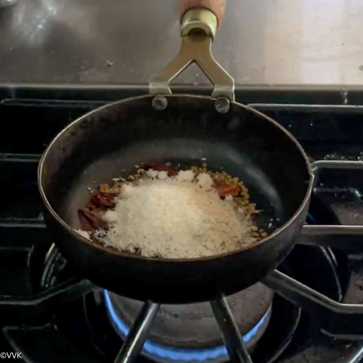 adding the spices to the kadai for roasting