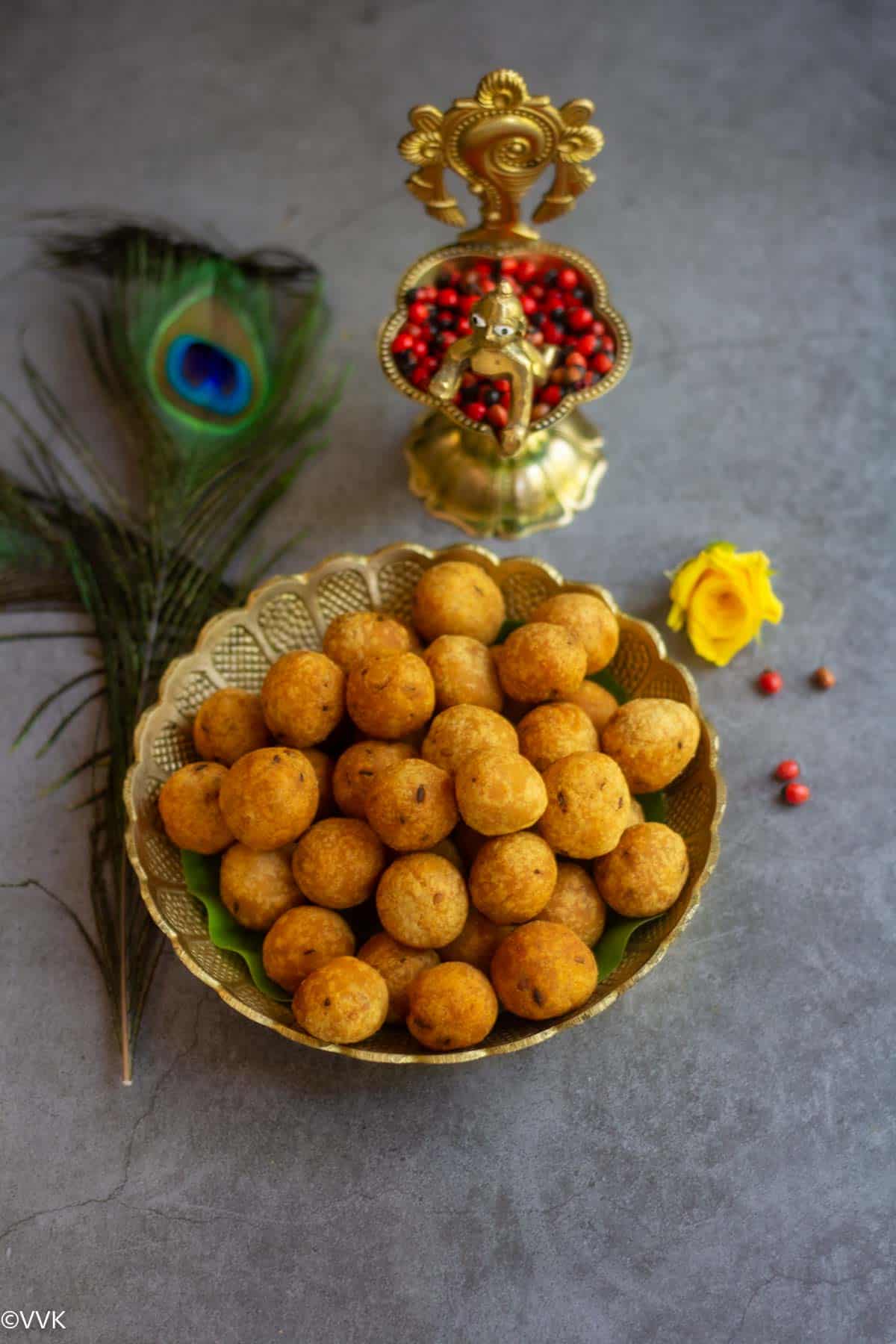 crispy seedai served in bronze plate with krishna lamp on the side with peacock feathers