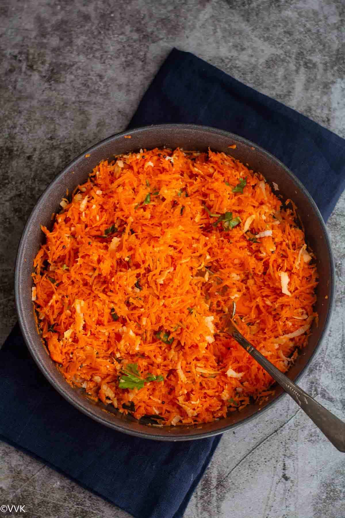 overhead shot of carrot salad served in gray bowl placed on blue towel