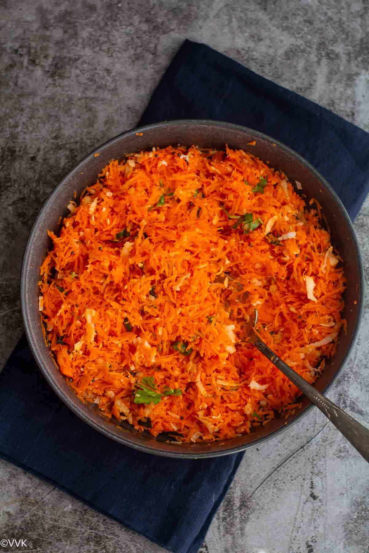 overhead shot of carrot kosambari served in gray bowl placed on blue towel