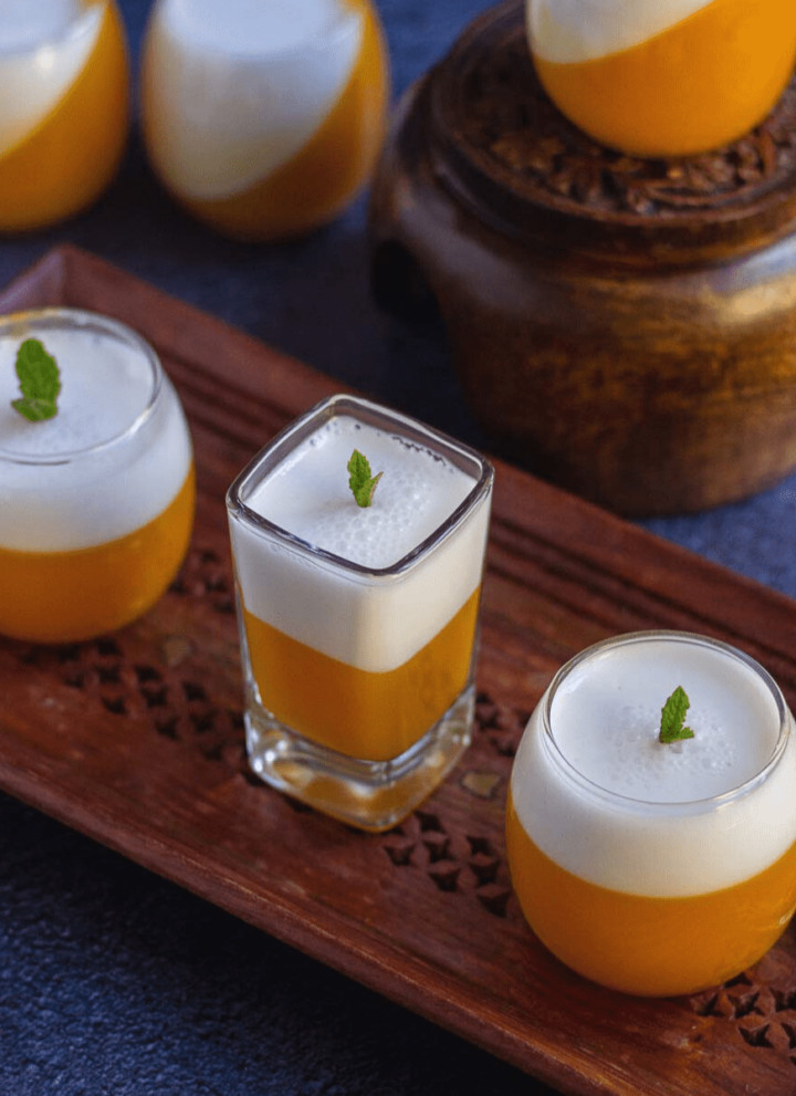 mango coconut jello served in single serve glasses placed on wooden tray
