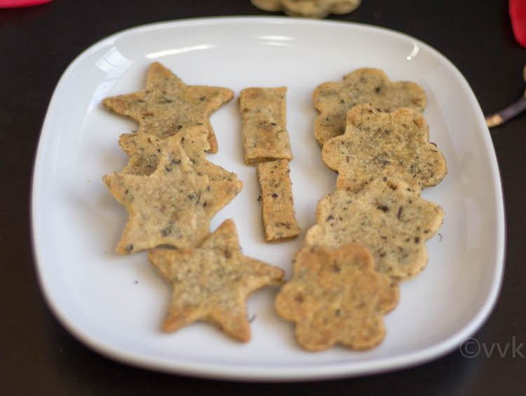 Baked Methi Mathri cookies of various shapes presented on a big white plate