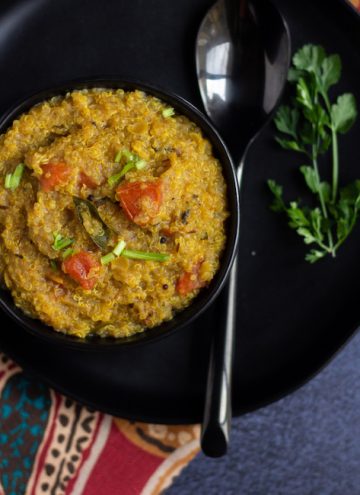 one pot rasam rice place on a black bowl with cilantro and a spoon on the side