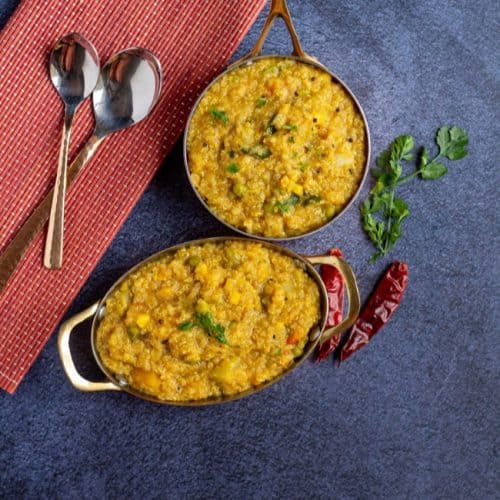 quinoa sambar sadham in tow brassware with red chilies on the side