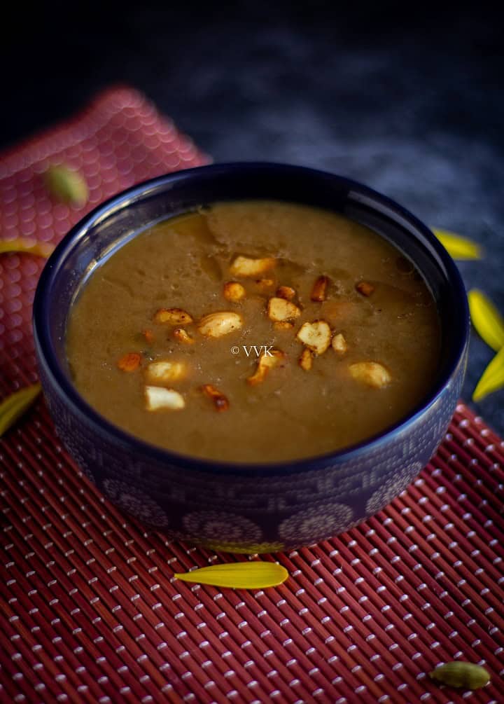 easy pasi paruppu payasam served in a blue bowl with cashew tempering placed on a red mat