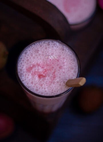 square shot of lychee lassi with wooden spoon inside