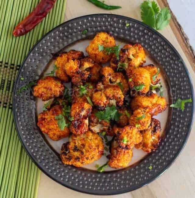 overhead shot of cauliflower bites served on a plate placed on wooden board