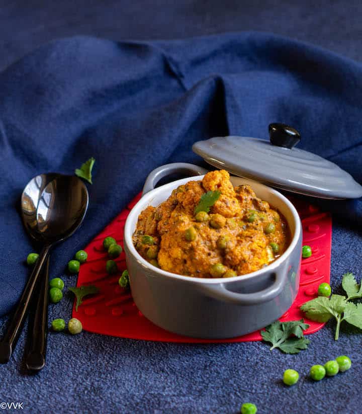 gobi matar served in a gray casserole placed on a red coaster