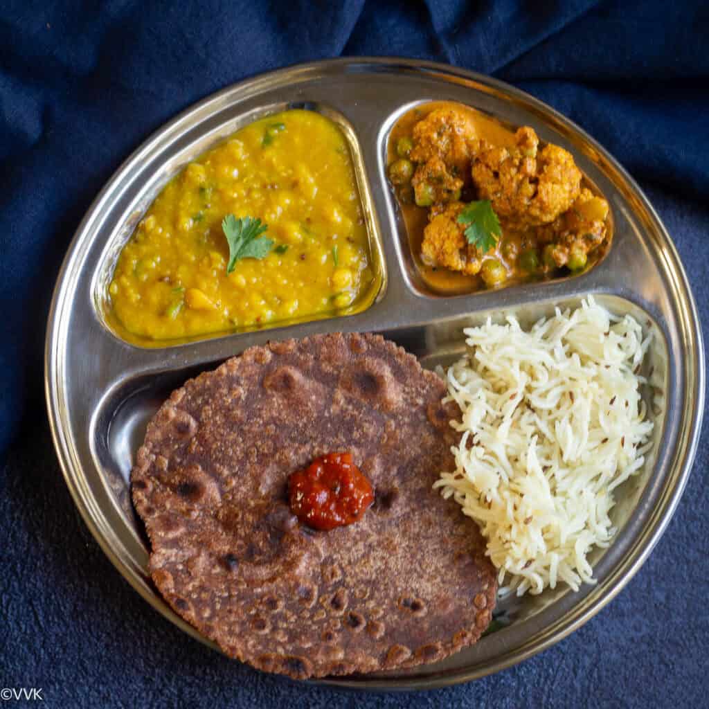 simple indian thali served on a partioned plate with four dishes - dal, rice, curry and roti
