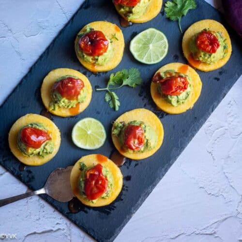 overhead square image of polenta bites placed on a black slate board