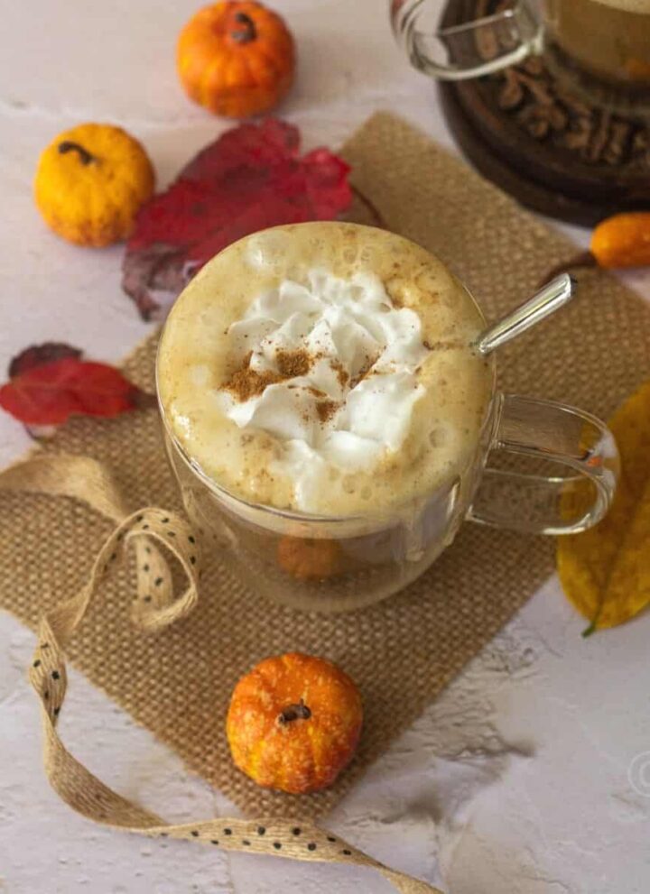 square image of pumpkin spice latte served in a glass placed on a burlap cloth