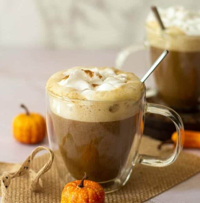 straight angle shot of pumpkin spice latte topped with coconut whipping cream