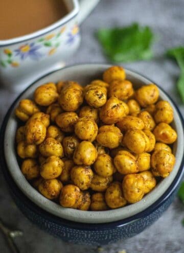 crunchy air fryer chickpeas served in bowl with tea on the side and cilantro as a garnish