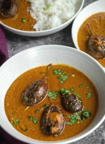 bagara baingan served in white bowl with curry and rice on the side