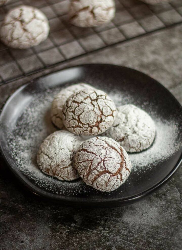 square image of crinkle cookies placed in black plate with powdered sugar