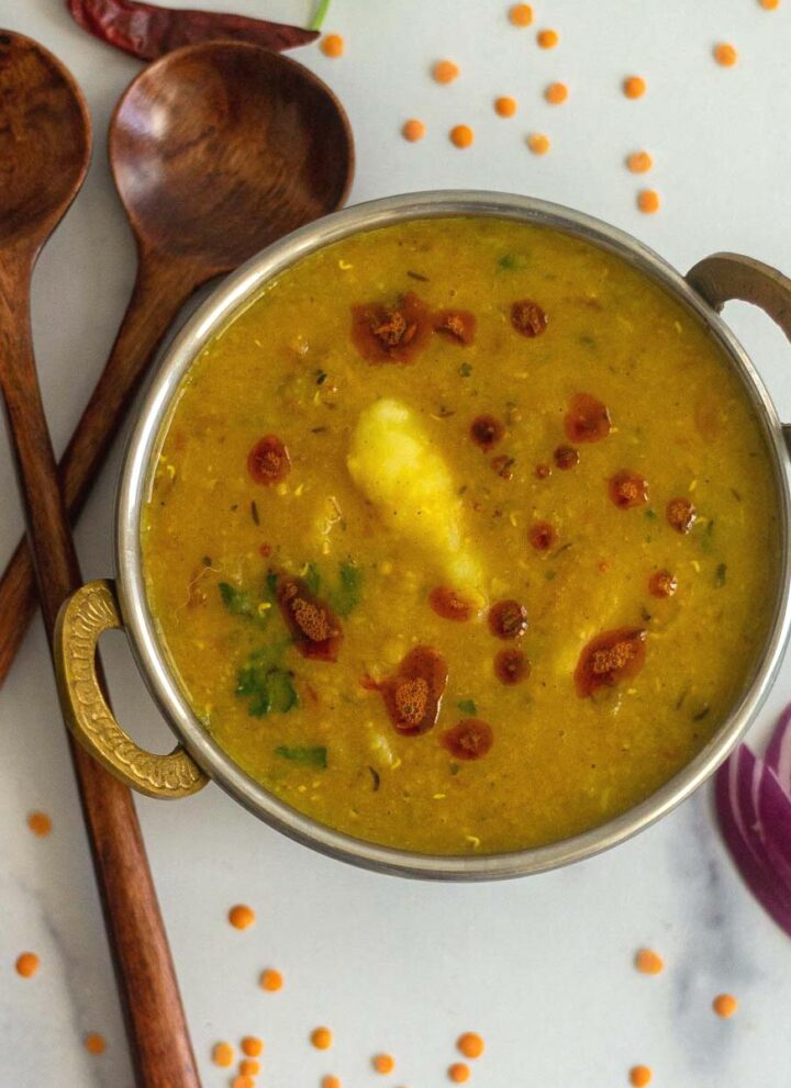 overhead shot of aloo masoor dal served in a brassware kadai