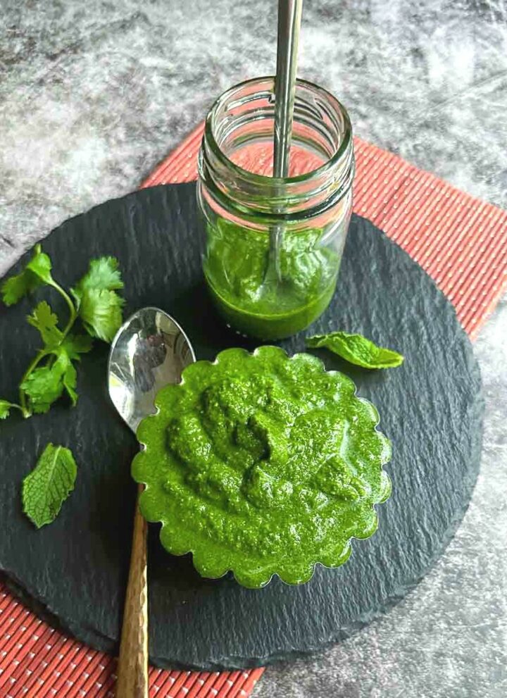 square image of green chutney served in bowl and bottle