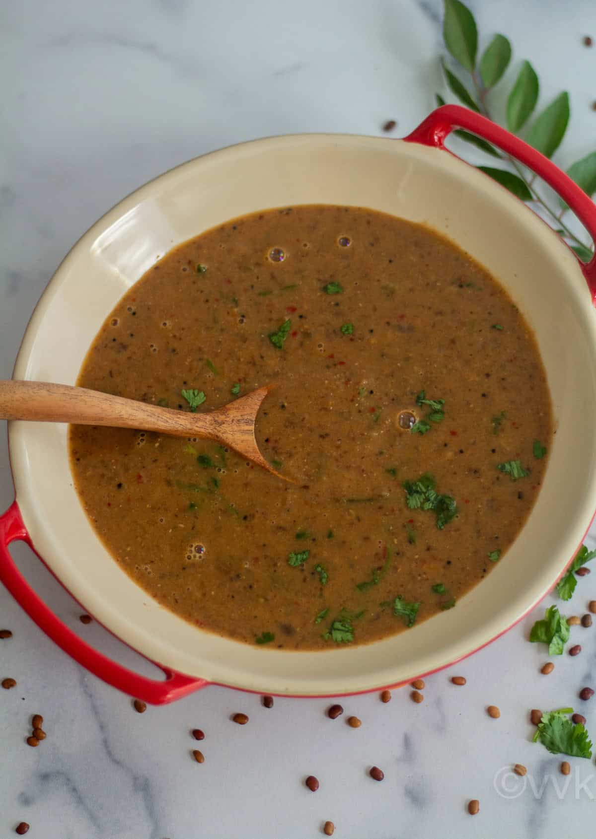 horsegram lentil curry served in ceramic ware with wooden spoon inside