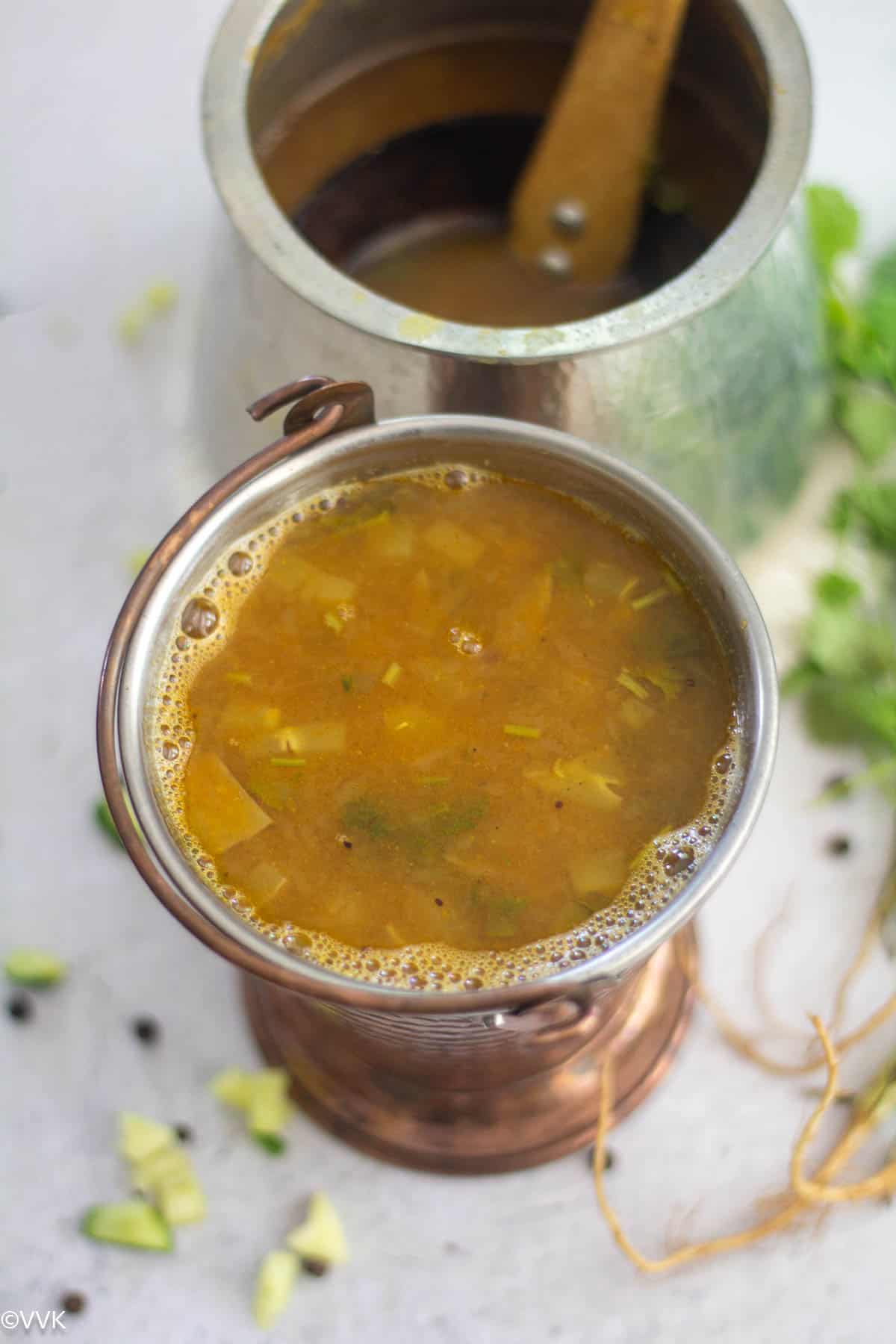 mavinikayi saaru served in brass vessel with rasam on eeya sombu on the side