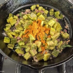 adding cooked bitter gourd, spices and salt