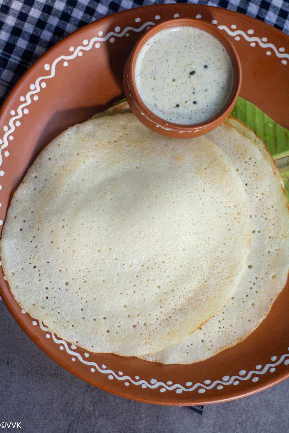 Stack of watermelon rind dosa served on banana leaf placed on a plate with a side of chutney