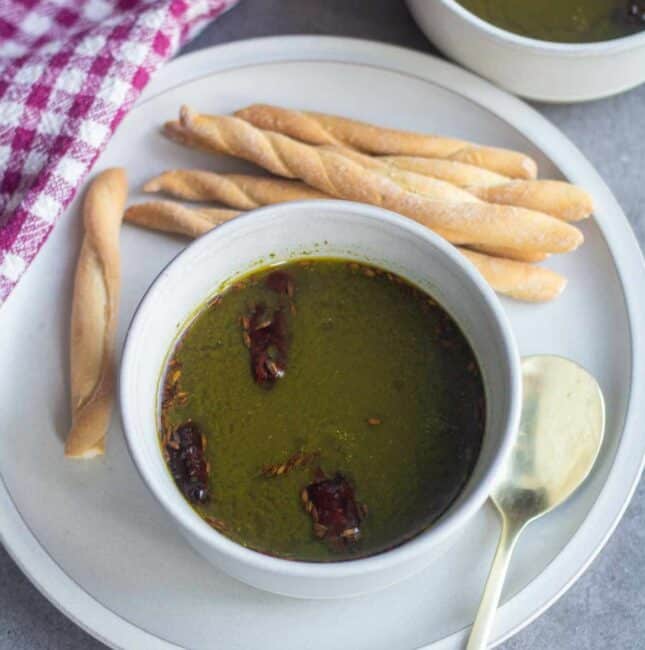 square image of moringa soup served in white bowl.