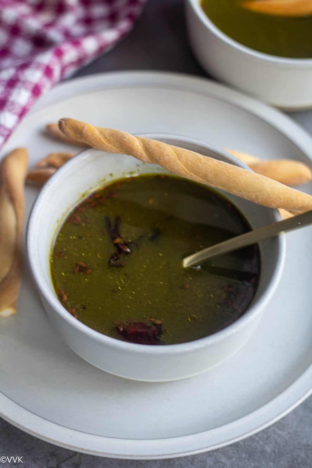 close up shot of moringa leaves soup with bread stick on top