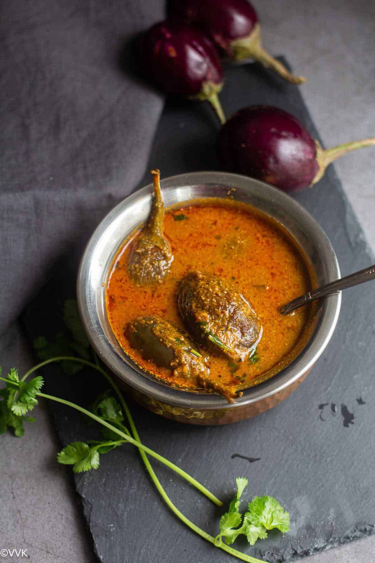 tangy aubergine gravy served in brassware with brinjals on the side