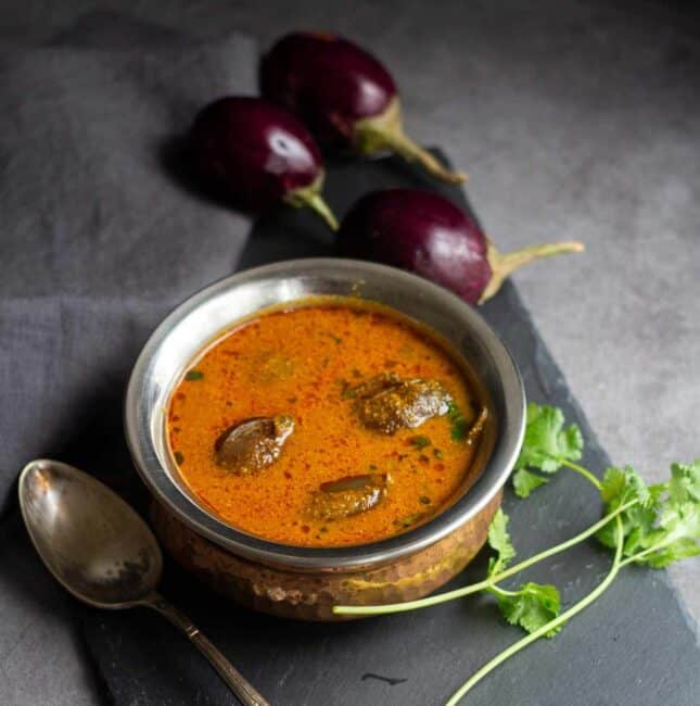 square image of brinjal gravy served in brassware