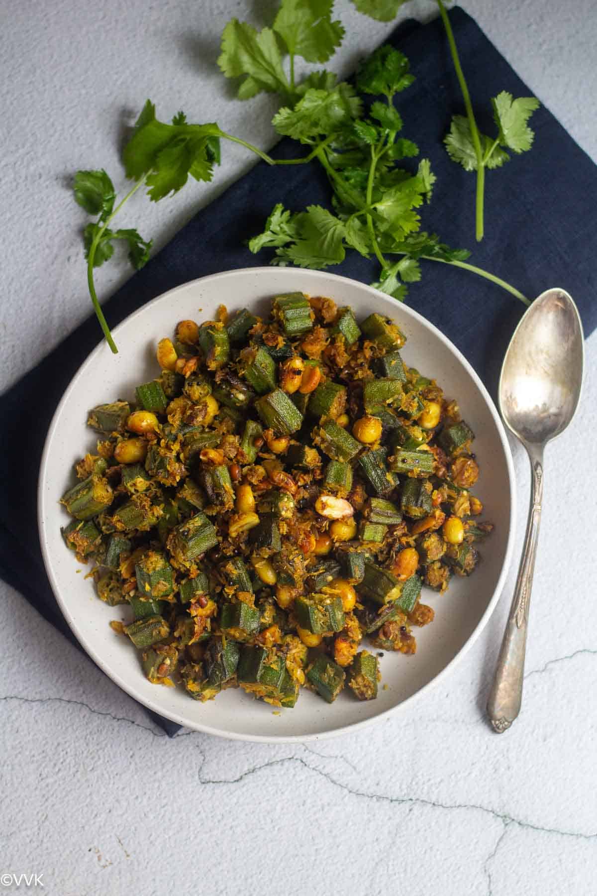 overhead shot of okra curry with spoon on the side and cilantro on the side